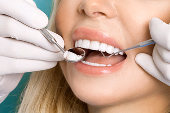 Dentist wearing white gloves examining a patient's teeth using a dental mirror and explorer.